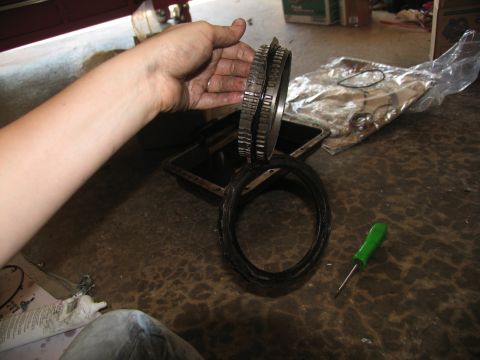 1978 Ford Bronco - Damaged transmission gear set held over an oil pan, suggesting a rebuild is underway.