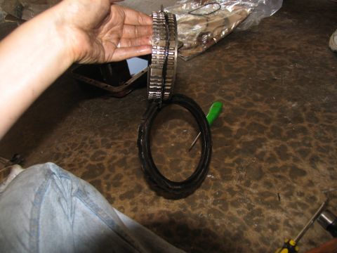 1978 Ford Bronco - A person holds a transmission clutch pack and a rubber seal over a dirty floor with tools nearby.