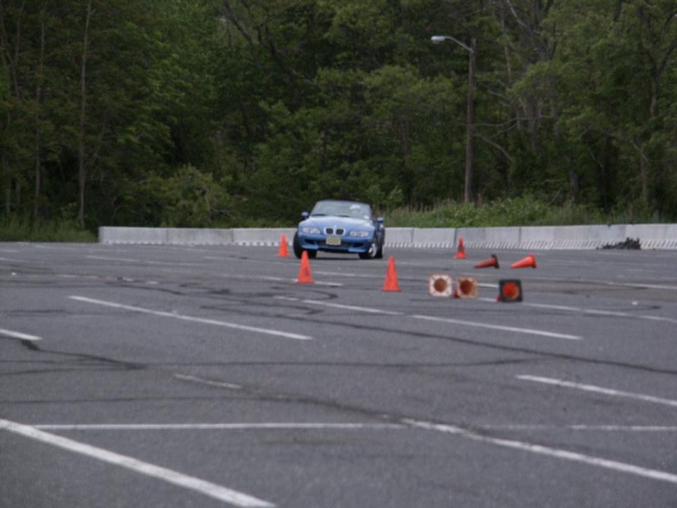 Blue convertible sports car on a paved lot with orange cones