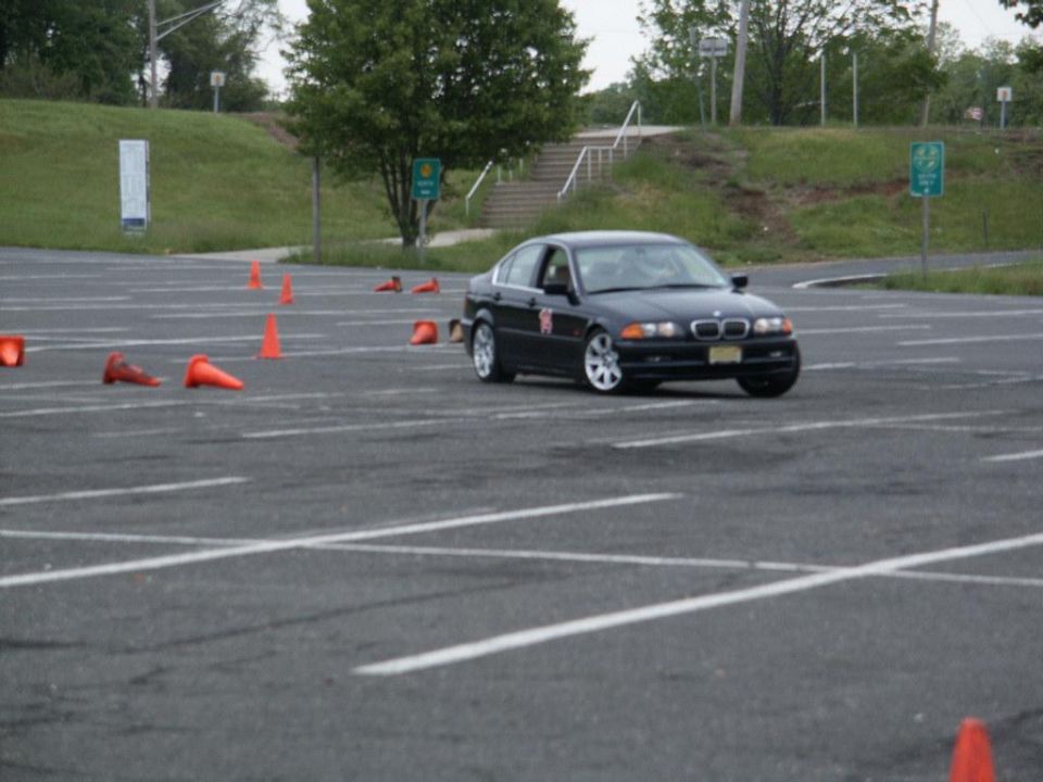 Black BMW sedan on a race track with cones, front 3/4 view