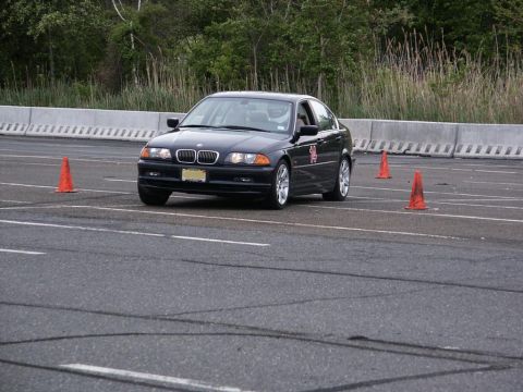 2001 Mercury Grand Marquis - A black BMW 3 Series sedan is shown on an asphalt course, maneuvering around orange traffic cones during a timed event.