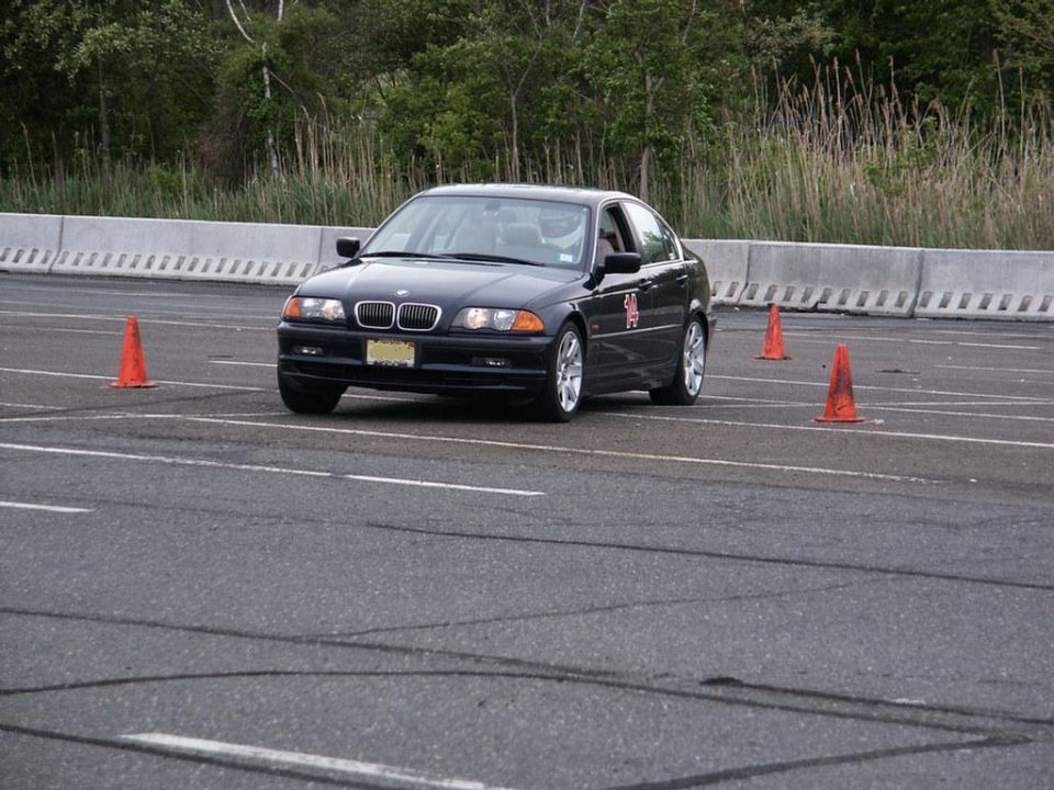 Black BMW 3 Series sedan navigating an autocross course with orange cones