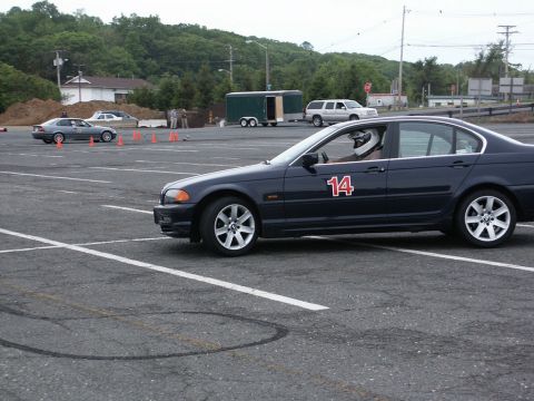 2001 Mercury Grand Marquis - A dark blue sedan with racing number 14 on the door is seen on a track with other vehicles in the background.