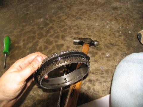 1978 Ford Bronco - A damaged transmission part is held in a hand, with tools visible on the concrete floor.