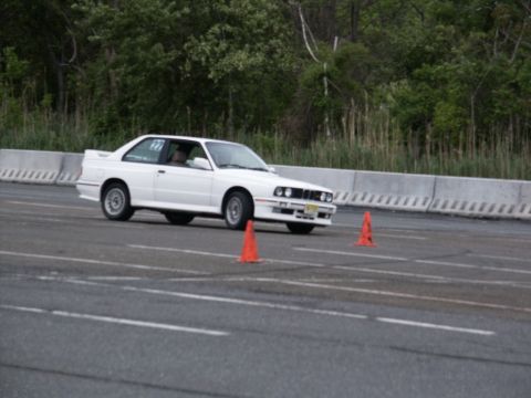 2001 Mercury Grand Marquis - A white BMW E30 M3 navigates a course marked by orange cones on a paved track.