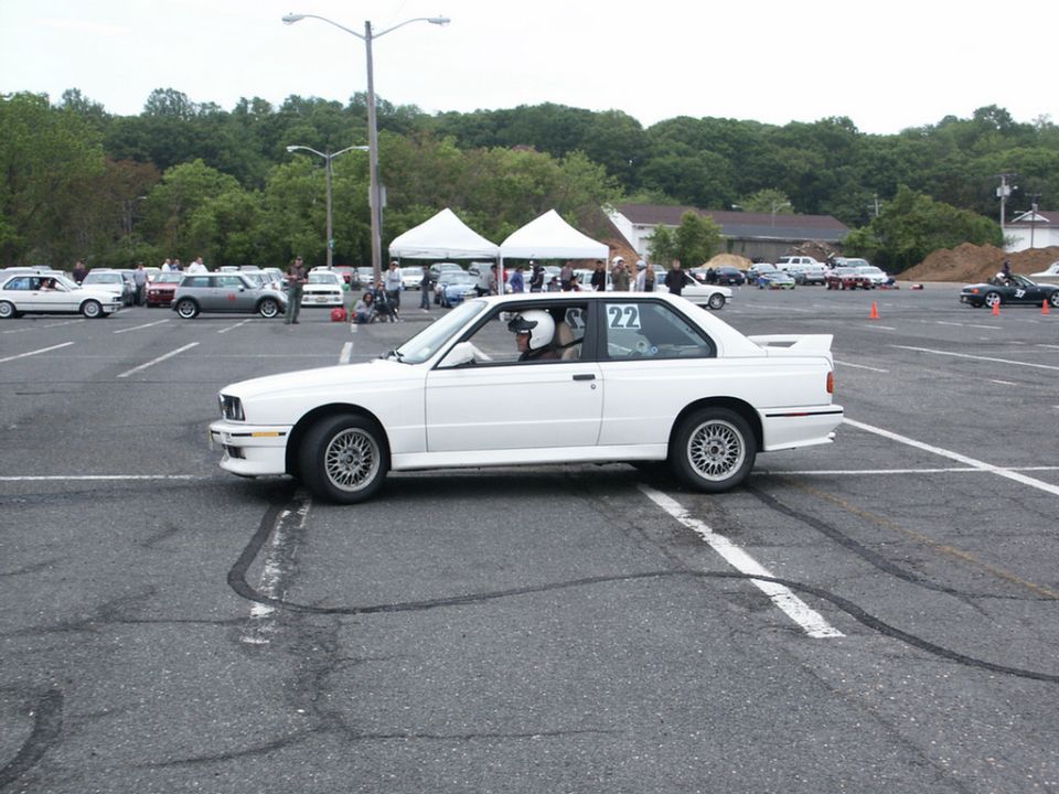 White coupe with racing driver and number 22 on door, side view, parked in lot with other cars