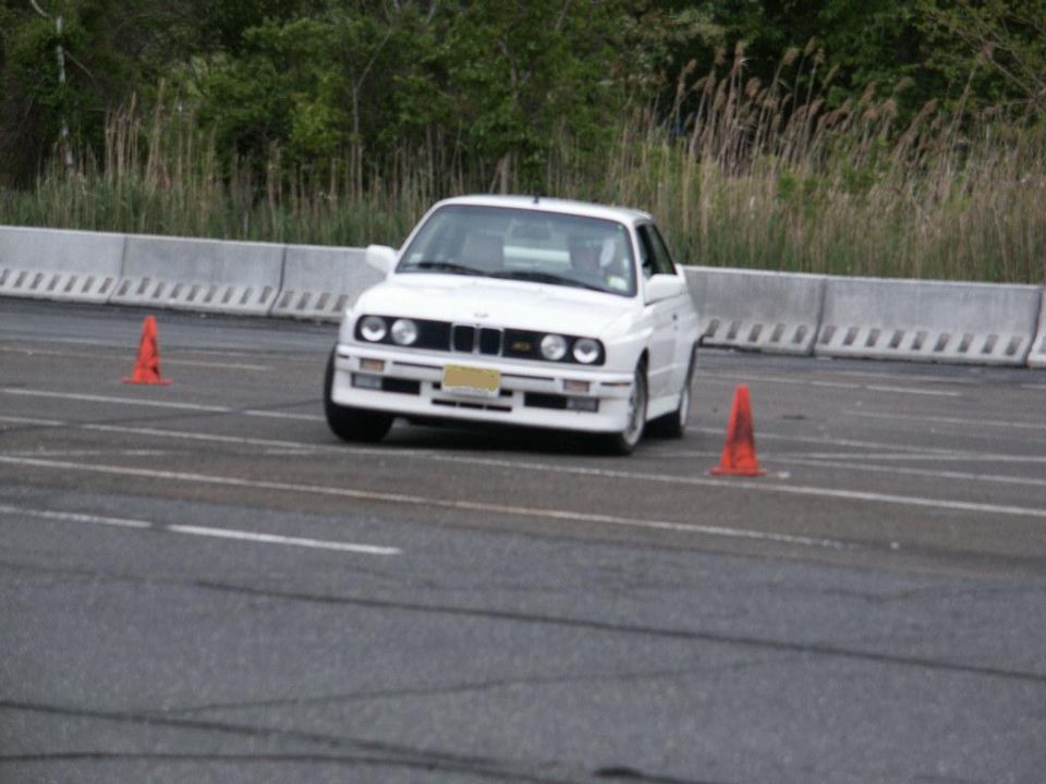 White BMW E30 M3 driving on a track with orange cones