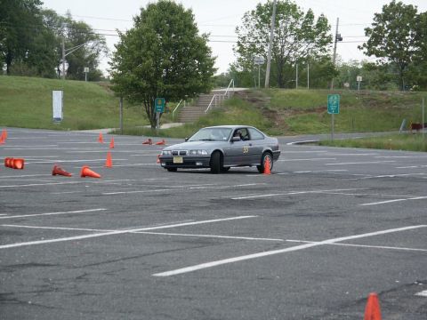 2001 Mercury Grand Marquis - A gray BMW E36 coupe is seen maneuvering through an autocross course marked by orange cones.