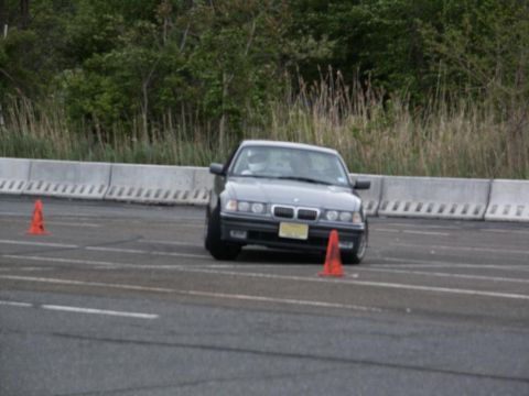 2001 Mercury Grand Marquis - A gray BMW E36 sedan is seen on an autocross course, maneuvering around orange cones.