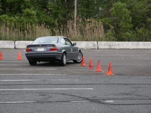 2001 Mercury Grand Marquis - A gray BMW E36 coupe is seen maneuvering through an autocross course marked by orange cones.