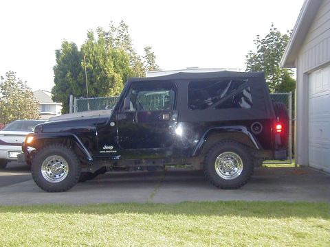 1994 Ford Explorer - Side view of a black Jeep Wrangler Unlimited parked in a driveway.