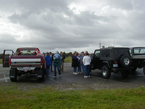 1994 Ford Explorer - People gathered in a parking lot with several vehicles under a cloudy sky.