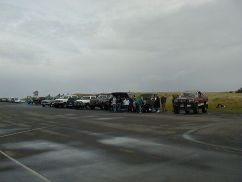 1994 Ford Explorer - A group of people stand around several SUVs and trucks parked in a line on a cloudy day.