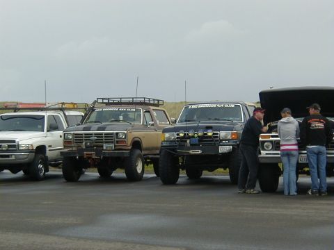 1994 Ford Explorer - Several modified trucks and SUVs are gathered, with people inspecting engines on two of them.