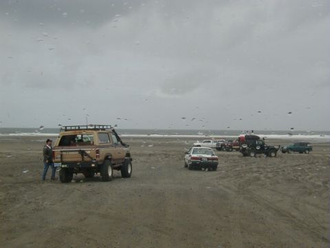 1994 Ford Explorer - A group of vehicles are gathered on a beach on an overcast day.