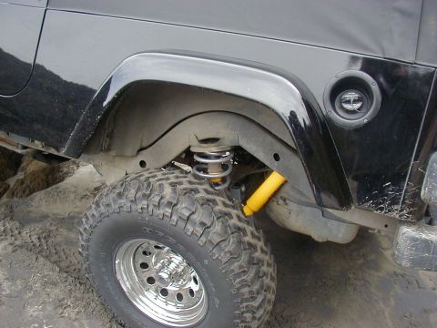 1994 Ford Explorer - Close-up of a black Jeep Wrangler's rear suspension and tire, showing off-road modifications.