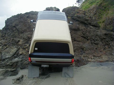 1994 Ford Explorer - Ford Bronco with camper shell parked on beach near rocks, license plate 927-L00.