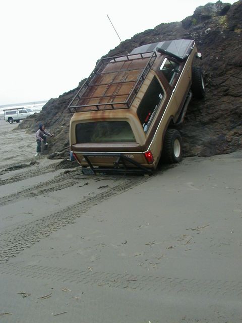 1994 Ford Explorer - This modified SUV is attempting to ascend a rocky embankment on a sandy beach, with another vehicle visible in the background.