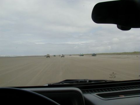 1994 Ford Explorer - Multiple vehicles drive along a vast, flat beach with the ocean visible in the distance.