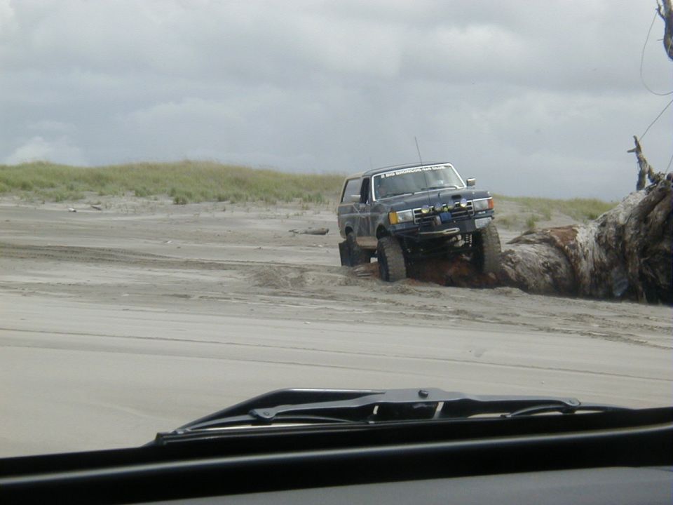 Dark blue SUV with off-road tires and lights on a sandy beach