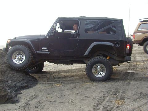 1994 Ford Explorer - A black Jeep Wrangler Unlimited navigates sandy terrain, with another vehicle visible in the background.