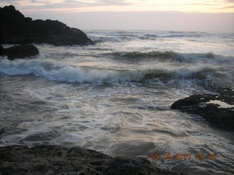 1994 Ford Explorer - The ocean churns with waves breaking against dark rocks under a hazy sky.