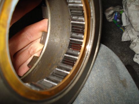 1984 Ford Bronco - A close-up view of a toothed metal ring, possibly a transmission component, with a hand inspecting it.
