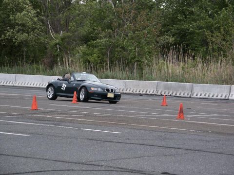 2001 Mercury Grand Marquis - A dark convertible sports car, identified by the number 37 on its door, navigates an autocross course marked by orange cones.