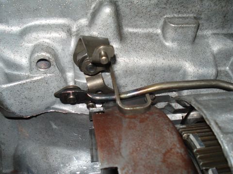 1984 Ford Bronco - Close-up view of a transmission linkage mechanism, showing rusty metal parts and mechanical linkages.