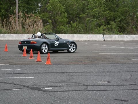 2001 Mercury Grand Marquis - A dark green convertible sports car, identified as a BMW Z3 by its body style and wheels, navigates an autocross course marked by orange co…