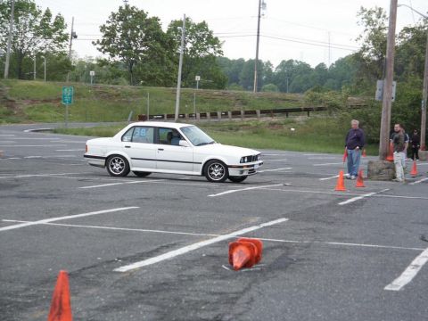 2001 Mercury Grand Marquis - A white BMW sedan navigates a course marked by orange cones in a parking lot.