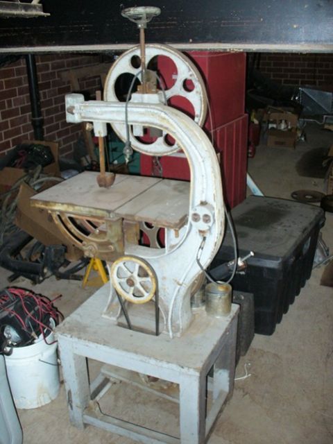 1990 Ford Bronco - A vintage bandsaw is pictured in a workshop setting, surrounded by various tools and storage containers.