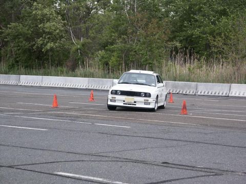 2001 Mercury Grand Marquis - A white BMW E30 navigates a cone course on a paved track.
