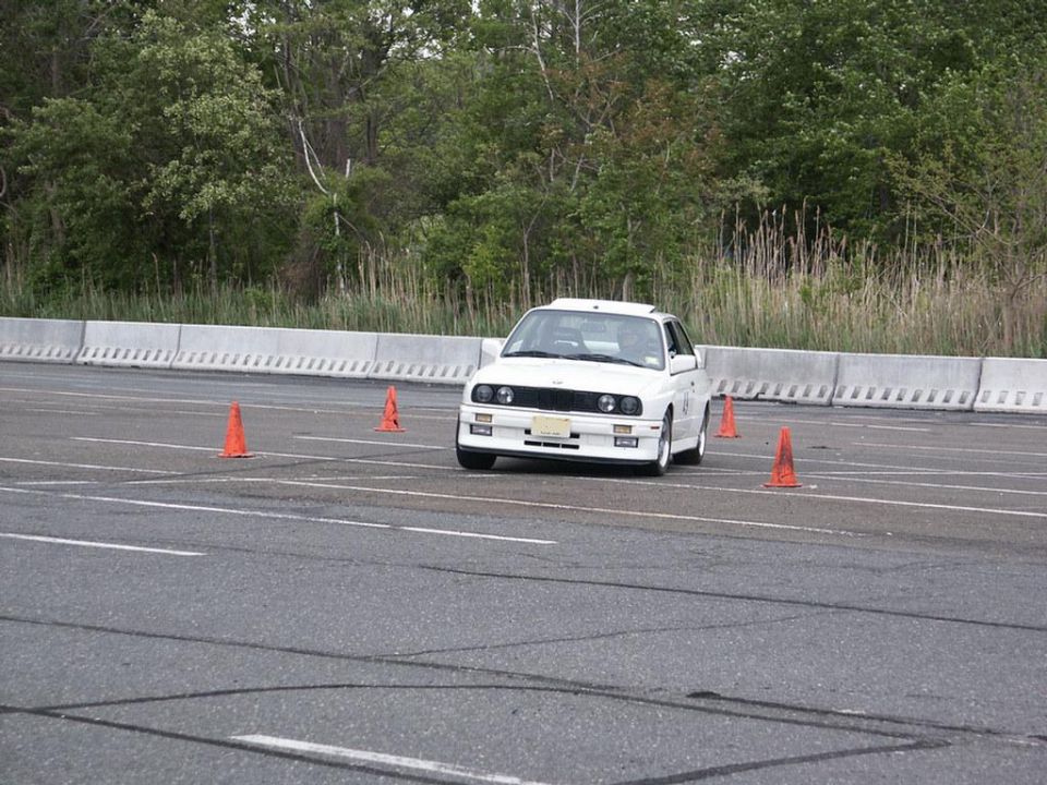 White BMW E30 on asphalt course with orange cones