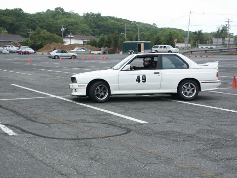 2001 Mercury Grand Marquis - A white BMW E30 M3 with racing number 49 participates in an autocross event on a paved course.