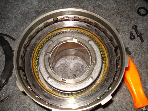 1984 Ford Bronco - Close-up view of a transmission drum assembly, showing clutch plates and seals, with an orange tool nearby.