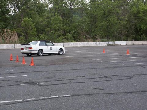 2001 Mercury Grand Marquis - White BMW E30 coupe with racing number 49 on door is seen on an asphalt lot with orange cones.