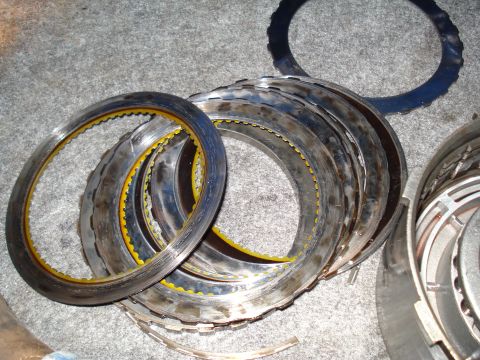 1984 Ford Bronco - Transmission clutch plates, likely from a rebuild, are laid out on a carpeted surface.