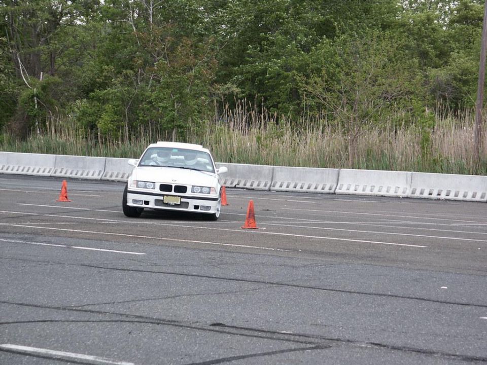 White BMW E36 sedan navigating a course marked by orange cones