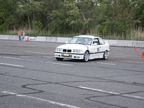 2001 Mercury Grand Marquis - A white BMW E36 coupe navigates a race track, marked with the number 50 and surrounded by cones.