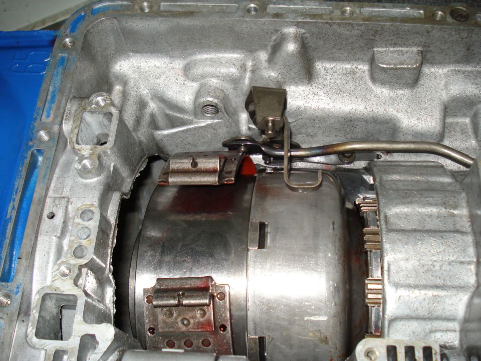 Transmission torque converter with red fluid visible, metal casing, and clips