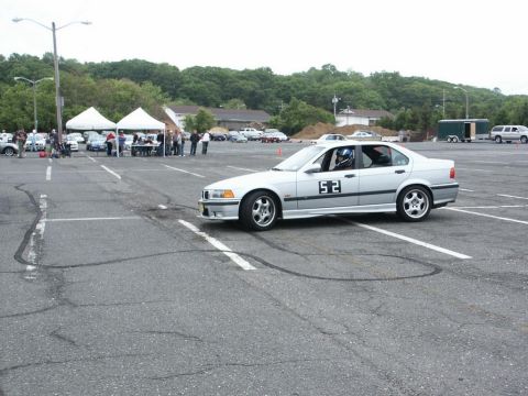 2001 Mercury Grand Marquis - A silver sedan, possibly a BMW, is parked in a lot during an event with tents and other vehicles visible.