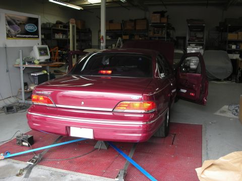 1992 Ford Crown Victoria - A maroon 1992 Ford Crown Victoria LX is positioned on a dynamometer in a garage, with its doors open and hood up.