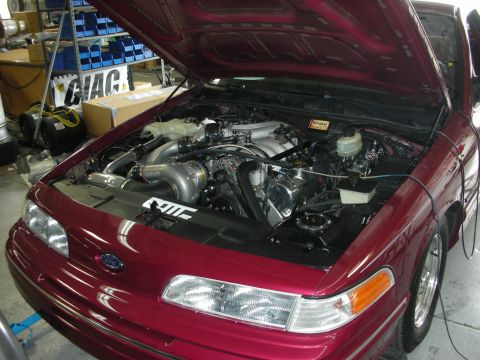 1992 Ford Crown Victoria - The engine bay of a 1992 Ford Crown Victoria is displayed with a prominent turbocharger and custom modifications.