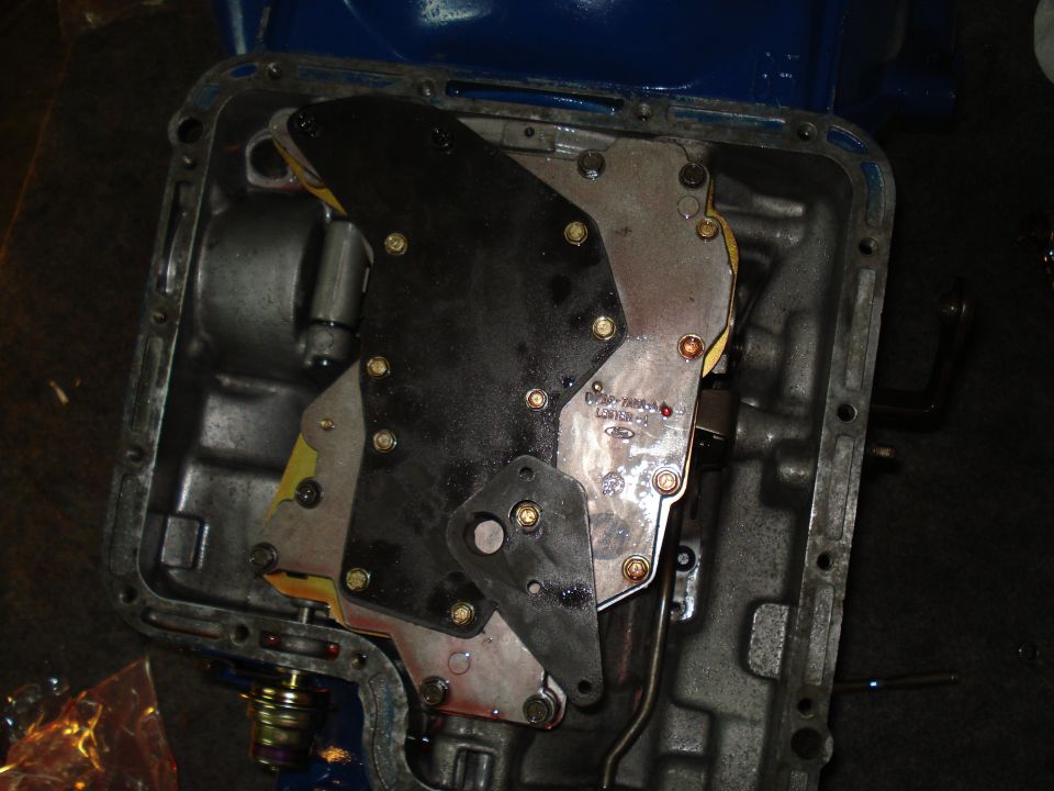 Transmission valve body with black and metal plates, visible springs and bolts