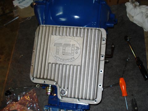 1984 Ford Bronco - A TCI Automotive transmission pan is shown with a blue transmission housing and tools nearby.