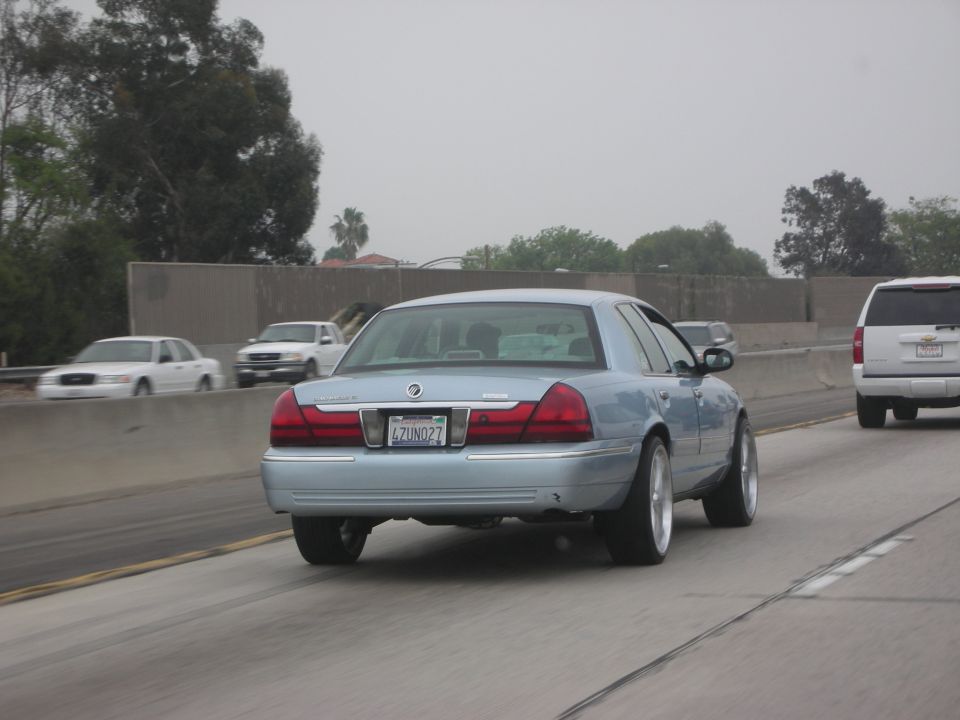 Light blue sedan with aftermarket wheels, rear view, California license plate 4ZUN027