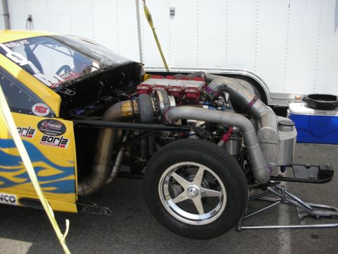1998 Ford Crown Victoria - A custom-built yellow drag car with its hood open, revealing a powerful engine and turbocharger setup.