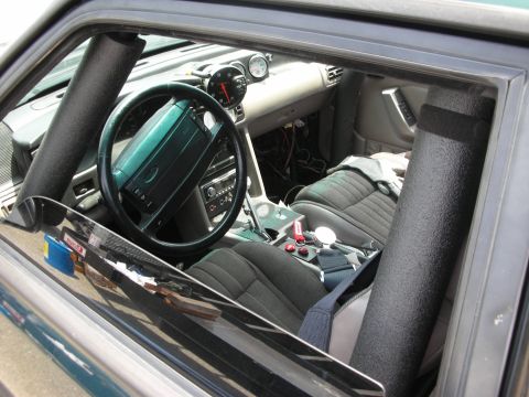 1998 Ford Crown Victoria - The interior of a modified car features racing seats, a roll cage, and additional gauges mounted on the dashboard.