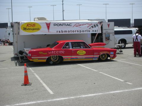 1998 Ford Crown Victoria - Drag racing car with racing decals parked next to a trailer at an event.